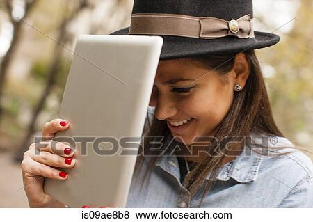Woman holding digital tablet to hat View Large Photo Image Stock Photo - Woman holding digital tablet to hat. Fotosearch