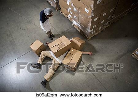 Woman looking at man lying on floor covered by cardboard boxes in warehouse View Large Photo Image Picture - Woman looking at man lying on floor covered by cardboard boxes in warehouse. Fotosearch