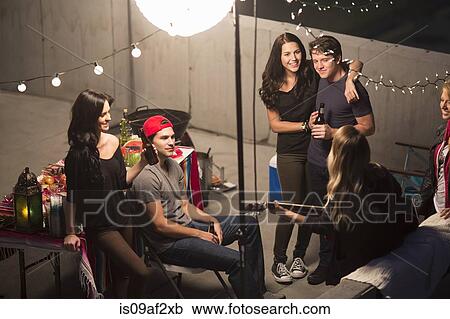 Young adult friends listening to guitar at rooftop party View Large Photo Image Stock Image - Young adult friends listening to guitar at rooftop party. Fotosearch