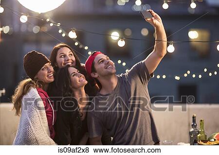 Young adult friends taking self portrait at party View Large Photo Image Stock Photo - Young adult friends taking self portrait at party. Fotosearch