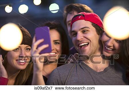 Stock Photo - Young adult friends taking selfie at party. Fotosearch
