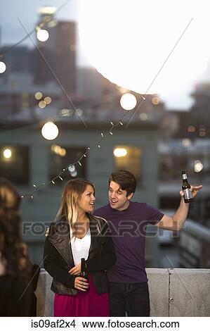 Picture - Young couple flirting at rooftop barbecue. Fotosearch
