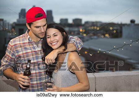 Stock Photo - Young couple having fun at rooftop barbecue. Fotosearch