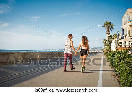 Stock Image - Young couple walking at San Diego beach. Fotosearch