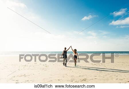 Young couple walking on San Diego beach, holding hands with arms raised View Large Photo Image Stock Image - Young couple walking on San Diego beach, holding hands with arms raised. Fotosearch