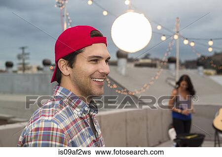 Young man in baseball cap at rooftop barbecue View Large Photo Image Stock Photograph - Young man in baseball cap at rooftop barbecue. Fotosearch