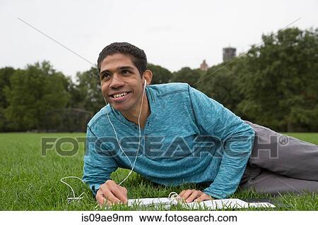 Young man lying on grass doing homework View Large Photo Image Picture - Young man lying on grass doing homework. Fotosearch