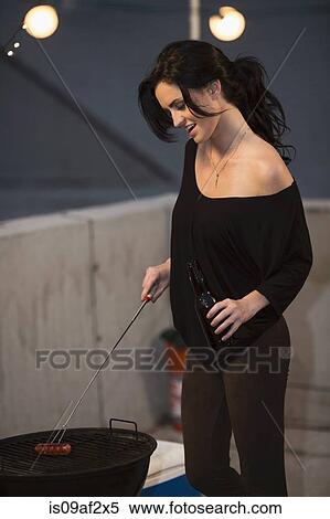 Young woman barbecuing at rooftop party View Large Photo Image Stock Photography - Young woman barbecuing at rooftop party. Fotosearch