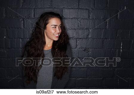 Stock Photo - Young woman by black brick wall. Fotosearch