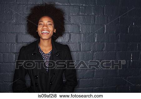 Stock Photo - Young woman by black brick wall wearing black jacket. Fotosearch