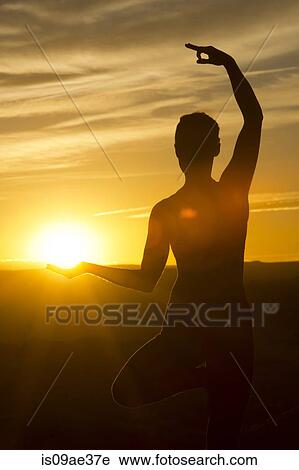 Stock Image - Young woman doing yoga in sunlight, Moab, Utah, USA. Fotosearch