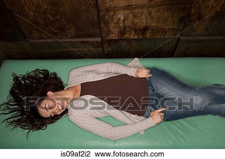 Stock Image - Young woman lying down on green mattress. Fotosearch