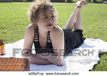 Young woman lying on picnic blanket in park View Large Photo Image Stock Photography - Young woman lying on picnic blanket in park. Fotosearch