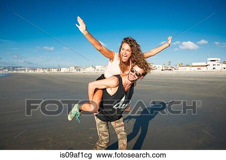Young woman on boyfriend's back with arms raised View Large Photo Image Stock Image - Young woman on boyfriend's back with arms raised. Fotosearch