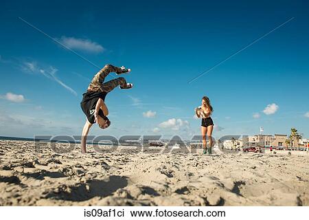 Young woman photographing boyfriend doing backflip on San Diego beach View Large Photo Image Stock Image - Young woman photographing boyfriend doing backflip on San Diego beach. Fotosearch