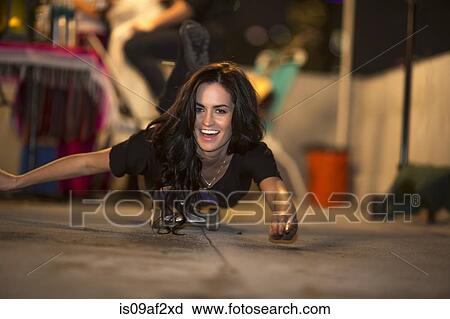 Stock Image - Young woman showing off on skateboard at rooftop party. Fotosearch
