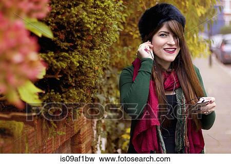 Young woman wearing winter clothing, holding smartphone View Large Photo Image Stock Photo - Young woman wearing winter clothing, holding smartphone. Fotosearch