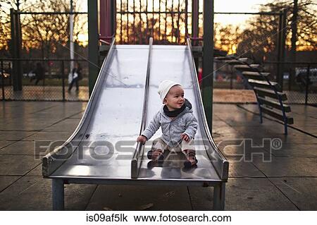 Baby boy sitting on slide in park View Large Photo Image Stock Image - Baby boy sitting on slide in park. Fotosearch