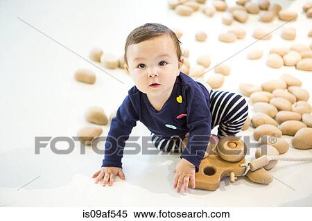 Stock Photography - Baby girl sitting on floor with toy. Fotosearch
