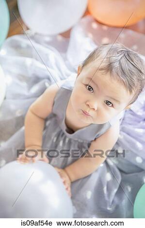 Stock Image - Baby girl wearing party dress with balloon. Fotosearch