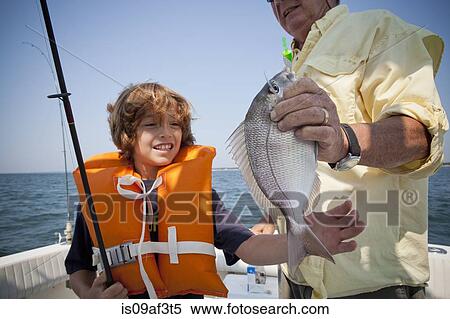 Stock Photography - Boy and grandfather with caught fish on boat, Falmouth, Massachusetts, USA. Fotosearch