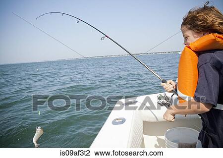 Stock Image - Boy catching fish from boat, Falmouth, Massachusetts, USA. Fotosearch