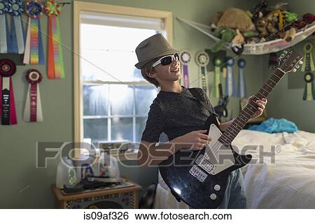 Stock Photograph - Boy playing guitar in bedroom. Fotosearch