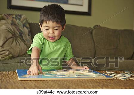 Boy playing puzzle in living room View Large Photo Image Stock Image - Boy playing puzzle in living room. Fotosearch