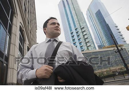 Businessman in city surrounded by skyscrapers View Large Photo Image Stock Image - Businessman in city surrounded by skyscrapers. Fotosearch