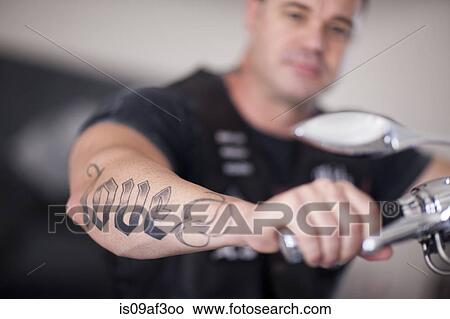 Picture - Close up of mature man sitting on motorcycle indoors. Fotosearch