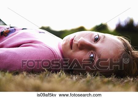 Stock Photo - Close up portrait of a girl lying on grass. Fotosearch