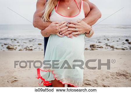 Stock Image - Cropped image of pregnant couple hugging. Fotosearch