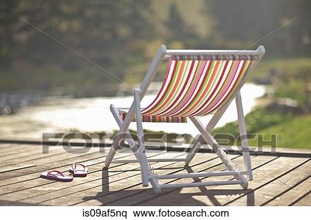 Deckchair and pair of flipflops on river pier View Large Photo Image Stock Photography - Deckchair and pair of flipflops on river pier. Fotosearch