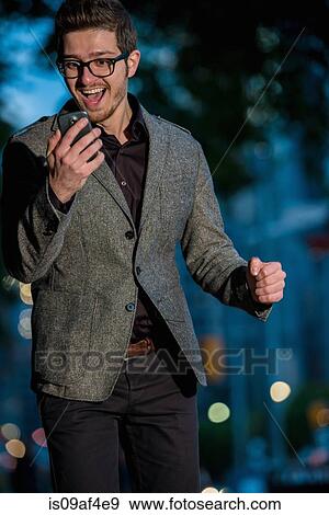 Excited young man looking at mobile phone, Toronto, Ontario, Canada View Large Photo Image Stock Photo - Excited young man looking at mobile phone, Toronto, Ontario, Canada. Fotosearch