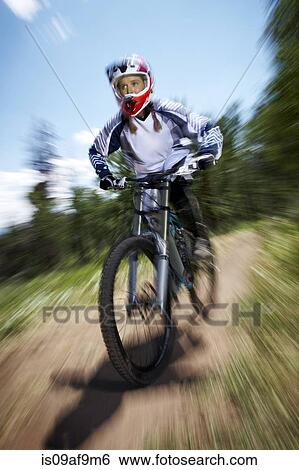 Stock Photograph - Female mountain biker speeding downhill. Fotosearch