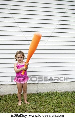 Female toddler in garden holding a large orange baseball bat View Large Photo Image Stock Photo - Female toddler in garden holding a large orange baseball bat. Fotosearch