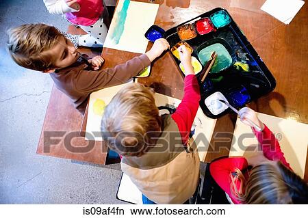 Four young siblings painting pictures at table View Large Photo Image Picture - Four young siblings painting pictures at table. Fotosearch