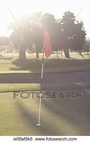 Stock Photography - Golf flag on golf course green at sunrise. Fotosearch