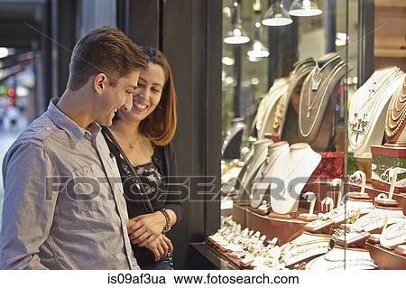 Stock Image - Happy couple looking at jewelry shop window. Fotosearch