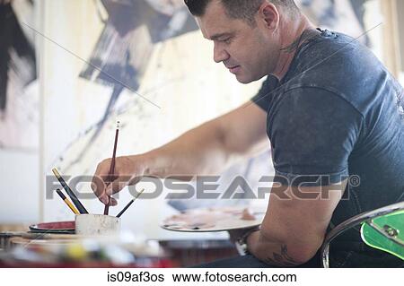 Stock Photograph - Mature male artist working on canvas in studio. Fotosearch