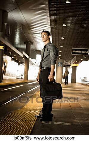 Stock Photograph - Mid adult businessman waiting for train at station. Fotosearch
