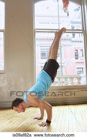 Stock Image - Mid adult man doing handstand. Fotosearch