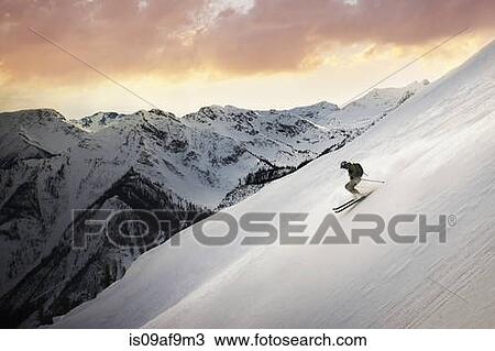 Stock Image - Mid adult man skiing down mountain, Golden, British Columbia, Canada. Fotosearch