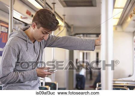 Mid adult man using cellphone on subway train View Large Photo Image Stock Image - Mid adult man using cellphone on subway train. Fotosearch