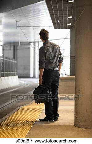 Mid adult office worker watching for train at station View Large Photo Image Stock Photography - Mid adult office worker watching for train at station. Fotosearch