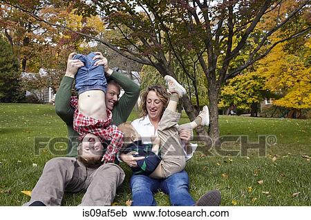 Mid adult parents and young sons playing in garden View Large Photo Image Stock Image - Mid adult parents and young sons playing in garden. Fotosearch
