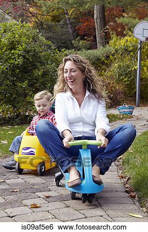 Mother and young son riding on toy cars in garden View Large Photo Image Stock Photograph - Mother and young son riding on toy cars in garden. Fotosearch