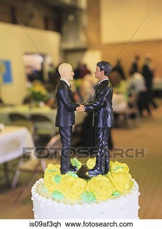 Stock Image - Pair of male figurines on top of wedding cake at reception. Fotosearch