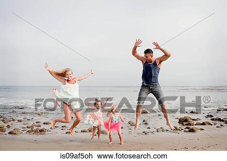 Parents and two young girls jumping mid air on beach View Large Photo Image Stock Image - Parents and two young girls jumping mid air on beach. Fotosearch