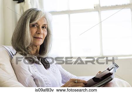Stock Photo - Portrait of attractive senior woman reading magazine. Fotosearch